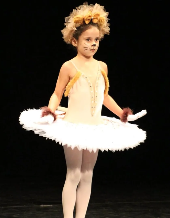 Bailarina infantil da Nery Company no palco, com figurino amarelo e tutu branco